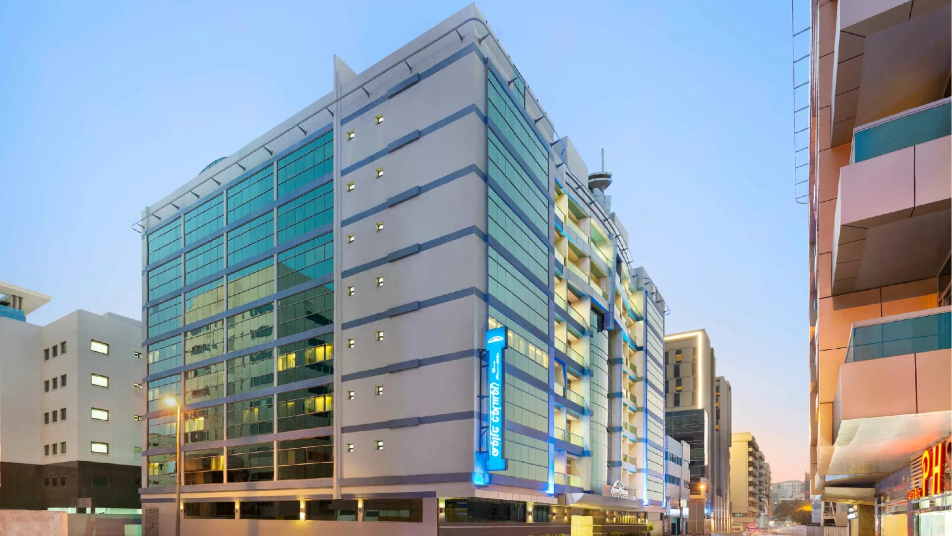 Howard Johnson Plaza by Wyndham Dubai Deira lit up on Al Rigga Street at dusk